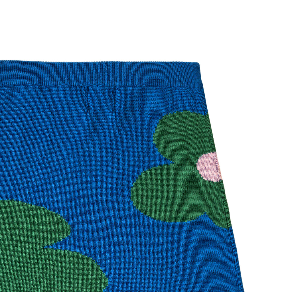 Blue fabric with green leaves and a pink center on a white background