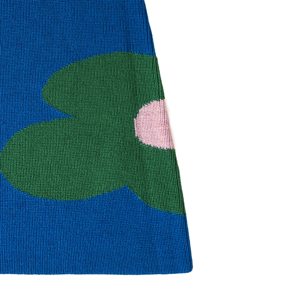 Close-up of a fabric with green heart shapes and a pink circle on a blue background