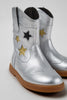 silver cowboy boot with gold and black stars on grey background.