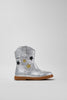silver cowboy boot with gold and black stars on grey background.