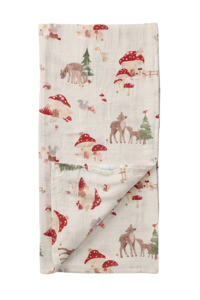 Folded fabric with forest-themed pattern featuring deer, mushrooms, and trees on a light background